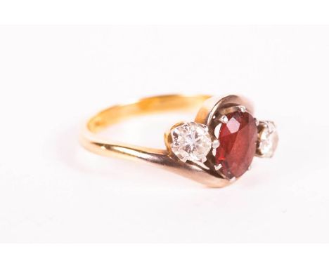 A garnet and diamond set trilogy ring, set in a yellow metal bypass mount. The garnet, an oval mixed cut, measures approximat