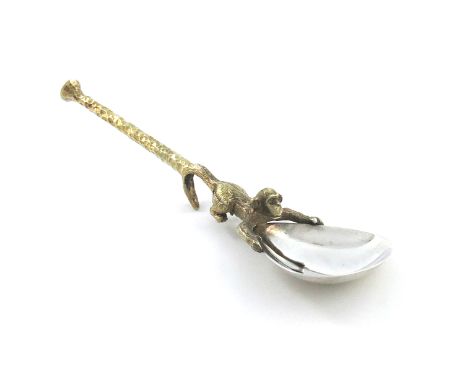 By Stuart Devlin, a modern parcel-gilt silver hook jam spoon, London 1974, the fig-shaped bowl held in two handles by a monke