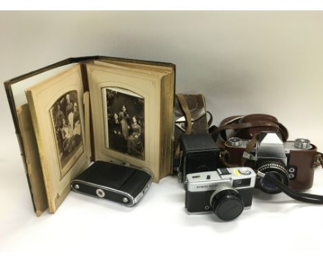 A collection of vintage cameras, a Victorian photo album and a circular wall barometer.