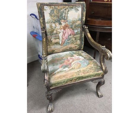 An Early 18th century style open arm chair with gilded scroll arms and legs and a tapestry covered back and seat.