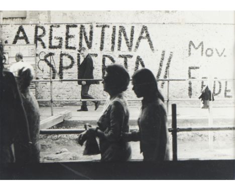 Sara Facio (Argentine, 1932-2024). Gelatin silver print photograph depicting figures walking along a graffiti-filled wall.Sig