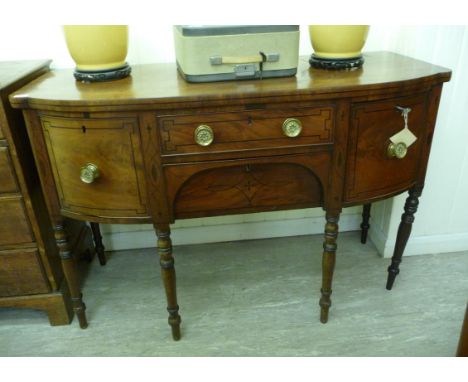 An early 19thC ebony inlaid mahogany bow front sideboard with two central drawers, flanked by a pair of cupboard doors, raise