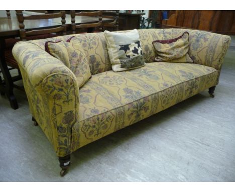 A late Victorian/Edwardian mahogany framed Chesterfield, upholstered in floral tapestry fabric, raised on ring turned, tapere