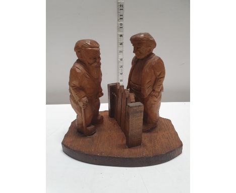 A carved figural group of two gentleman talking over a garden gate 