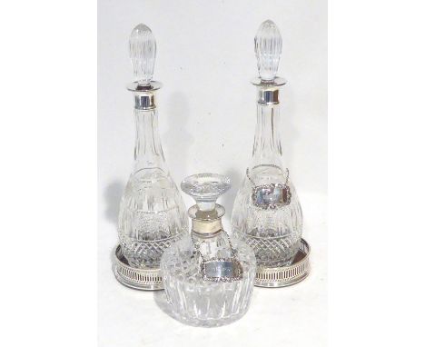 A PAIR OF CUT GLASS TALL SKITTLE SHAPED DECANTERS, with silver necks and fluted tear shaped stoppers, 15 1/2" (38.7cm) high, 
