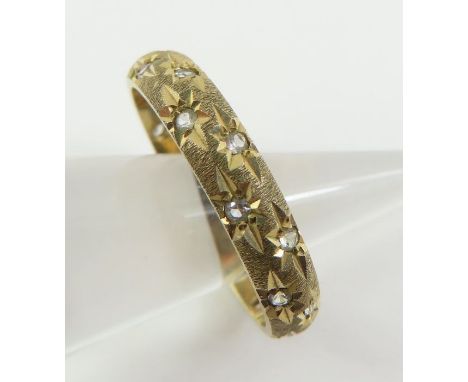 A 9ct gold diamond set band ring, each stone with star set decoration, satin finished band, finger size P, 2.65g gross