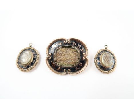 A Victorian hair panel mourning brooch; and a pair of hair panel mourning pendants; all pieces with black enamel decoration; 