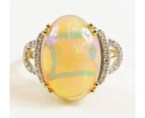 An 18ct gold Ethiopian opal and diamond dress ring, the oval opal 5.1cts and the diamonds 0.19ct total weight, finger size R,