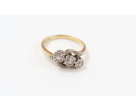 A three stone diamond cross over ring, stamped ‘18ct’ and ‘Plat’, the old brilliant cuts illusion set, finger size P, 4 g gro