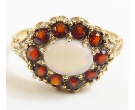 A 9ct gold opal and garnet cluster ring, the oval opal surrounded by ten round garnets, finger size P, 2.55g gross