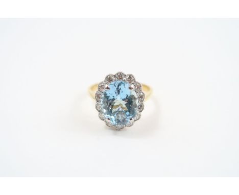 An 18ct gold aquamarine and diamond cluster ring, the oval mixed cut aquamarine approximately 12mm x 9.8mm x 6.7mm, approxima