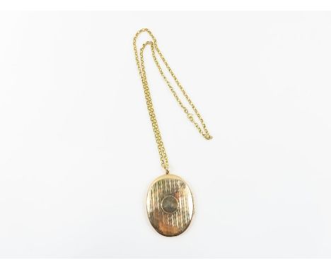A large 9 carat gold oval locket, Henry Matthews, Birmingham 1917, with linear engine turned decoration and vacant cartouche,