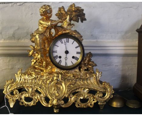 A 19th century French mantle clock with extensive ormolu carving, circular dial with Roman numerals, surrounded by a figurine