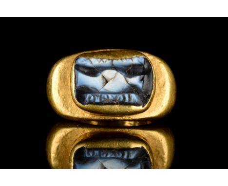 . A gold finger ring composed of a D-shaped, expanding hoop; raised oval-shaped bezel frame with a nicolo intaglio of 'dextra