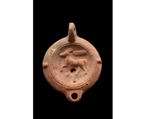 Ca. 1-200 AD. A very fine terracotta oil lamp depicting on the mirror a left-facing walking stag. The perimeter is decorated 