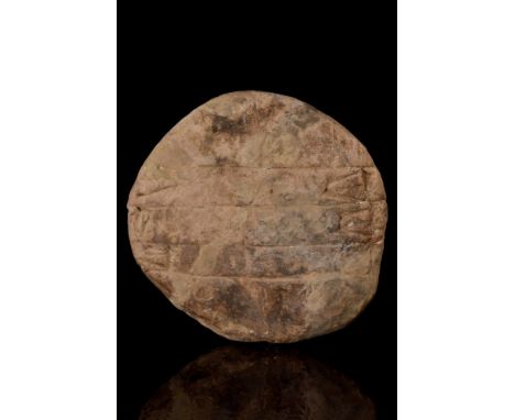 Ca. 2000-1600 BC. A round cuneiform tablet with four lines of cuneiform. These were used by students, who would typically wri