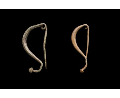 Ca. 300 BC. An interesting pair of La Tène I type bow brooches, each with a deep bow, pin to reverse, and a foot with a later