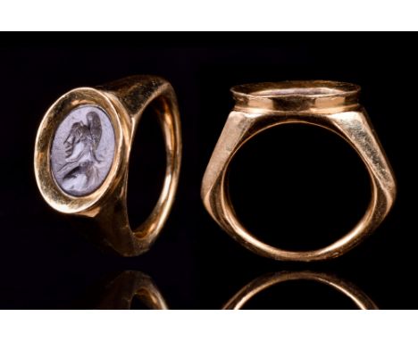 Ca. 200 AD. A heavy gold finger ring of a round hoop expanding to support a bezel set with a stone intaglio engraved with a b