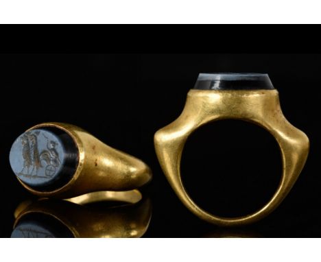 Ca. 100-300 AD. A fine Ancient Roman gold ring featuring a tapered, round band. The central feature is a nicolo intaglio set 