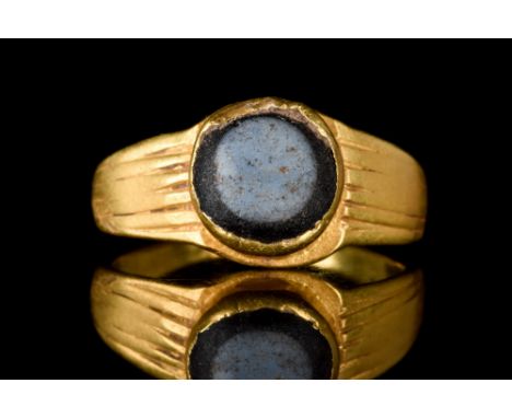 Ca. 100 -200 AD. A gold finger ring composed of a hoop expanding to ribbed shoulders. The bezel set with an oval eye agate st