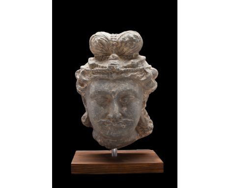 Ca. 200-300 AD. A schist head of a bodhisattva, with elaborate coiffure featuring a topknot (Ushnisha) and carefully-detailed