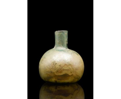 Ca. 100-200 AD. An elegant glass flask featuring a globular body leading to a narrow neck with a straight rim. The vessel sit