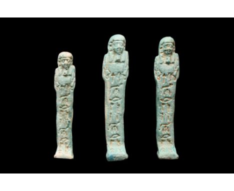 Late Period, 30th Dynasty, Ca. 332 BC. A group of three ushabti figures, each moulded in a light-blue, glazed faience, wearin