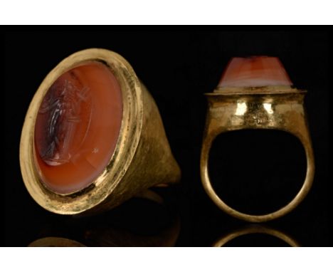 Ca. 200-300 AD. A gold ring with oval bezel and tapering band, the intaglio convex oval carnelian gem engraved with a winged 