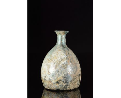 Ca. 100-300 AD. A pale blue free-blown glass flask featuring a domed body on a concave base with a pontil scar, a short cylin