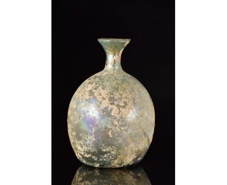 Ca. 100-300 AD. A free-blown glass flask featuring a squat, bulbous body on a concave base with a pontil scar, a short cylind