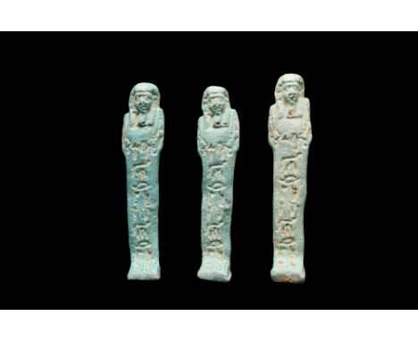 Late Period, 30th Dynasty, Ca. 332 BC. A group of three light blue faience ushabti figures, each wearing a tripartite wig, a 