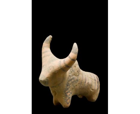 Ca. 3rd Millennium BC. A creme-coloured ceramic figurine of a zebu bull with rondel eyes. Painted with stripes on the back, s