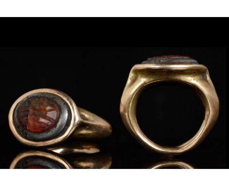 Ca. 100 AD. A gold ring with oval bezel and tapering band, the intaglio convex oval carnelian gem engraved with scene of hunt