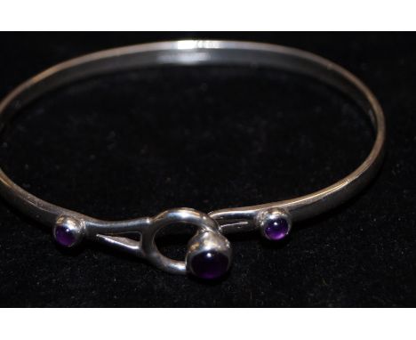 A silver bangle set with 3 purple stones