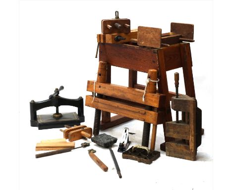 A collection of bookbinder's presses, on a pine stand, 70cm wide, together with lettering tools and block prints, and a copy 