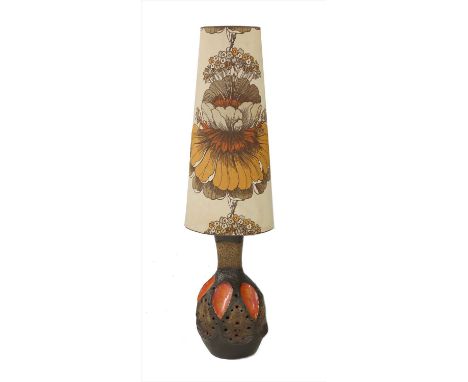 A glazed pottery lamp base, 1970s, with a printed shade, the moulded base with orange panels and pierced details, 135.5cm hig
