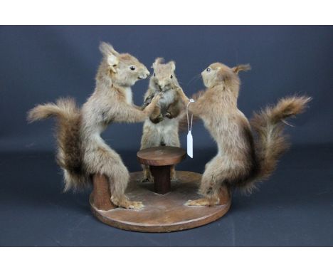 Taxidermy - A group of squirrels posed as playing cards, seated on stools about a circular table, 31cm high approx