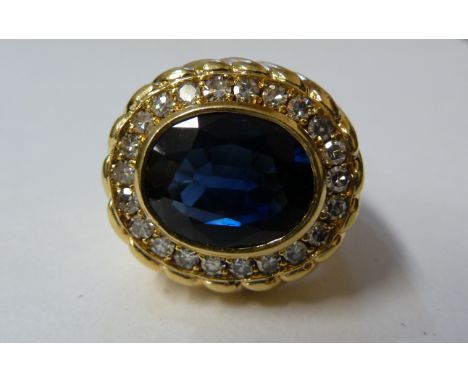 An impressive sapphire, diamond and yellow gold dress ring, the oval shaped mixed cut sapphire within a surround of circular 