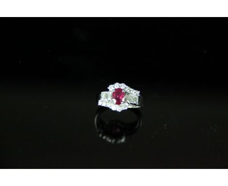 A ruby and diamond cluster ring, the oval shaped ruby with stepped baguette cut diamond shoulders and brilliant cut diamond d