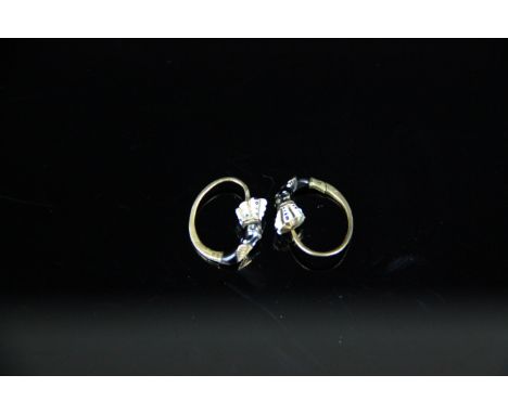 A pair of yellow metal and enamel hoop earrings, formed as blackamores with long plumed headdress in black white enamels, in 