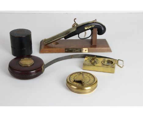 A Chesterman leather cased metal surveyors tape measure, 50ft; a flintlock pistol shaped lighter; a reproduction Gilbert sund
