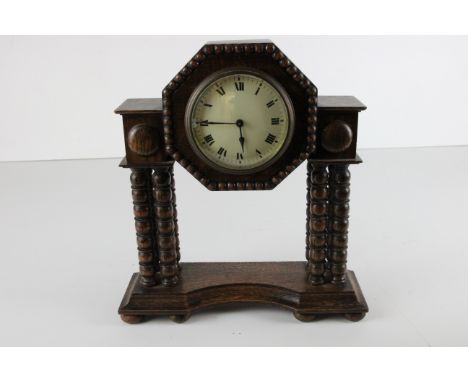 An early 20th Century oak cased mantle clock on bobbin turned supports - overall dimensions in cm are 29 high x 26 wide