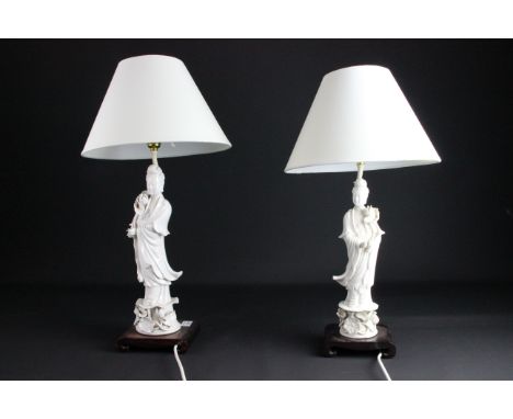 Pair of Chinese blanc de chine, porcelain figures of Guan Yin, fitted for electricity on scroll carved wooden bases, 34.5cm m