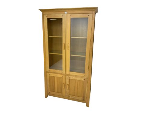 Light oak display cabinet, two glazed doors enclosing two glass shelves, over two panelled cupboards concealing single shelfD