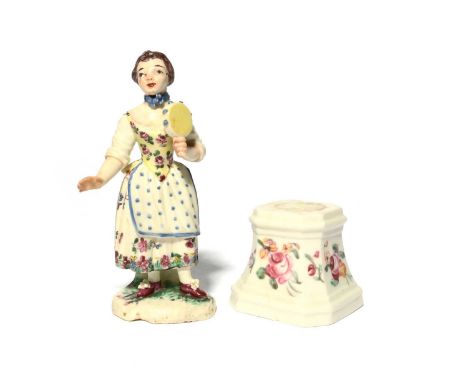 A Mennecy figure of a musician, c.1760-65, modelled as a young girl holding a tambourine and wearing a polka dot apron over a