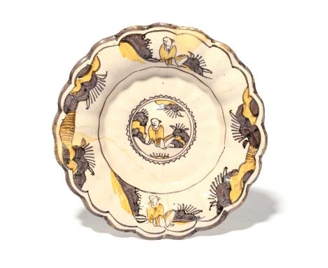 A small delftware lobed dish, c.1700, London or Brislington, painted in manganese and yellow with a Chinese figure seated in 