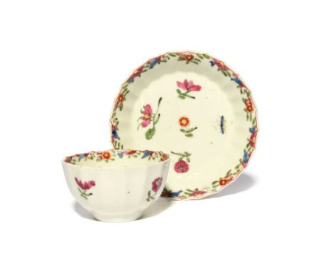 A Worcester teabowl and saucer, c.1765-70, of Warmstry fluted form, painted in polychrome enamels with scattered flower sprig
