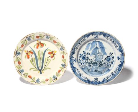 Two large delftware chargers, c.1750-70, one painted in blue with a willow tree issuing from rockwork within a zigzag fence, 