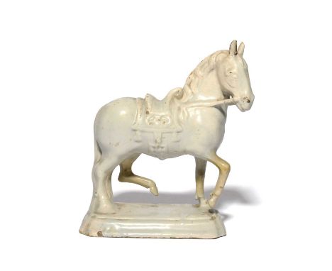 A Delft figure of a horse, mid 18th century, standing on a chamfered base with two hooves raised, wearing an elaborate saddle