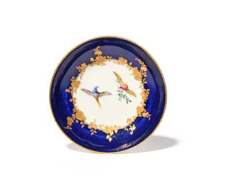 A Vincennes saucer, c.1755-56, painted with two colourful birds in flight, one holding a leafy branch, reserved within a gilt